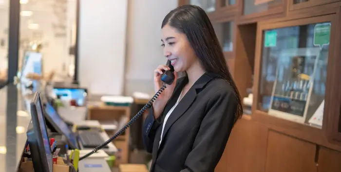 Hospitality and Hotels Hospitality worker on the phone at the receptionist desk