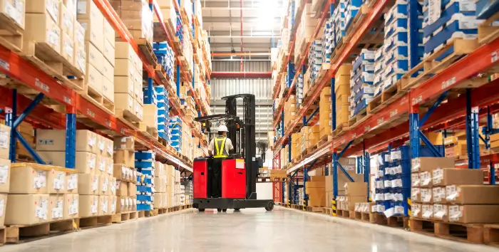 Warehouses and Storage Worker driving a forklift through the aisles of a warehouse