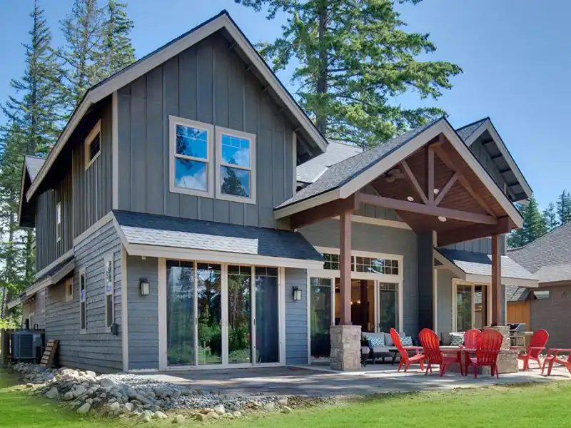 Large two-story residential house with gray siding, a blue front door, and a manicured front lawn.