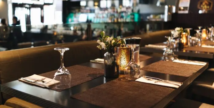 Intimate dining table setting at an upscale restaurant featuring woven placemats, wine glasses, and glowing candlelight